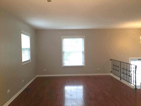 an empty living room with a hard wood floor and a staircase