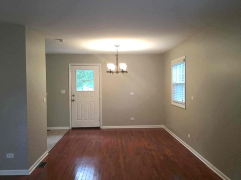 an empty living room with a wooden floor and a white door