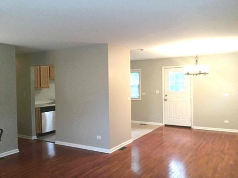 an empty living room and kitchen with a hard wood floor