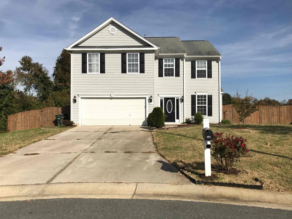 A two-story house with a garage and a mailbox in front.