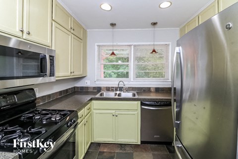 A kitchen with a stove top oven, microwave, sink, and refrigerator.