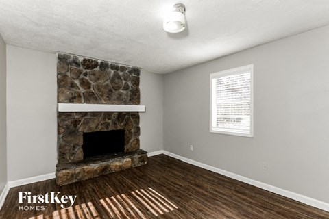 the living room has a stone fireplace and wood flooring