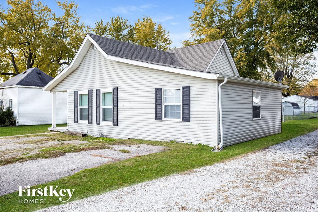 a white house with black shutters and a gravel driveway