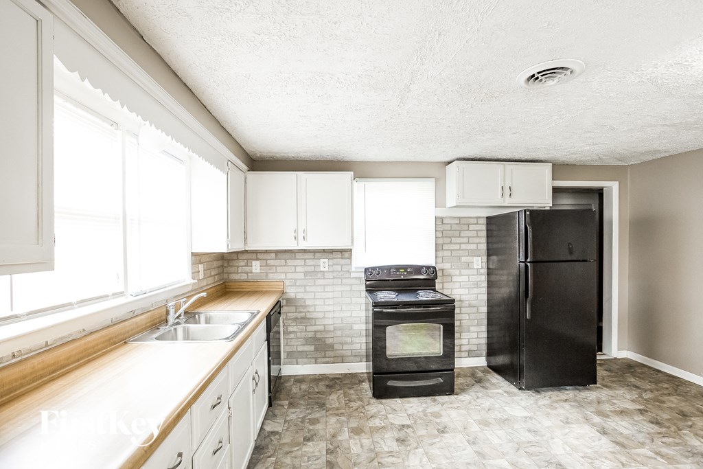 a kitchen with white cabinets and a black refrigerator