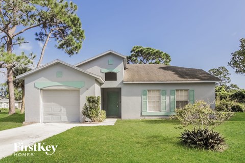 a light blue house with green shutters and a lawn