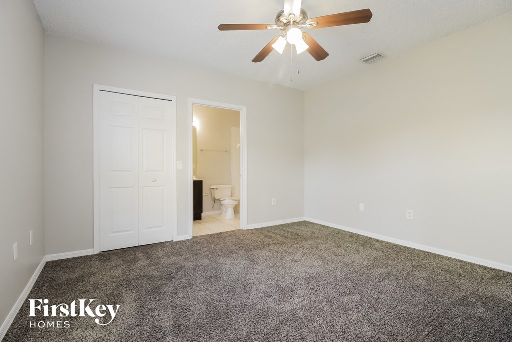 the spacious living room with carpeted flooring and a ceiling fan