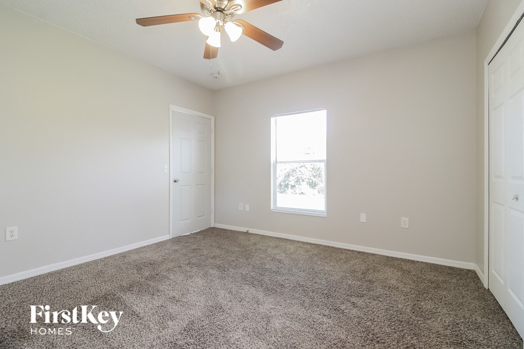 the spacious living room with carpeting and a ceiling fan