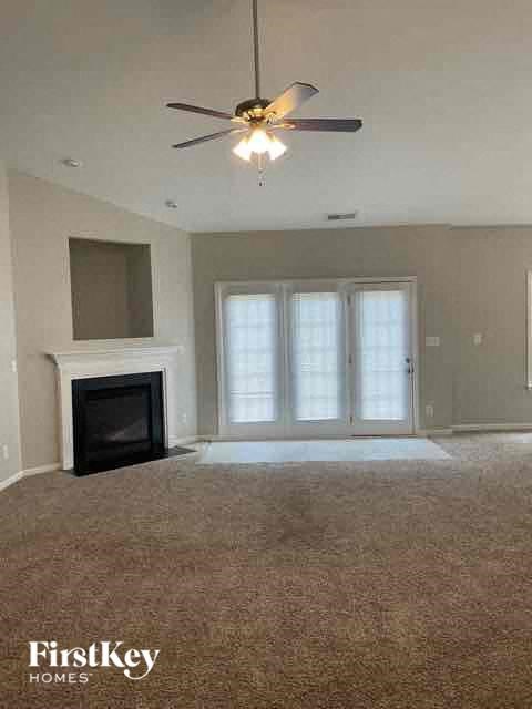A living room with a fireplace and a ceiling fan.