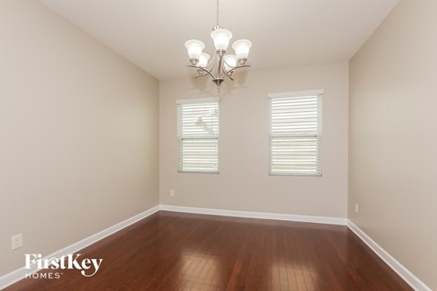 a empty dining room with wood floors and a chandelier
