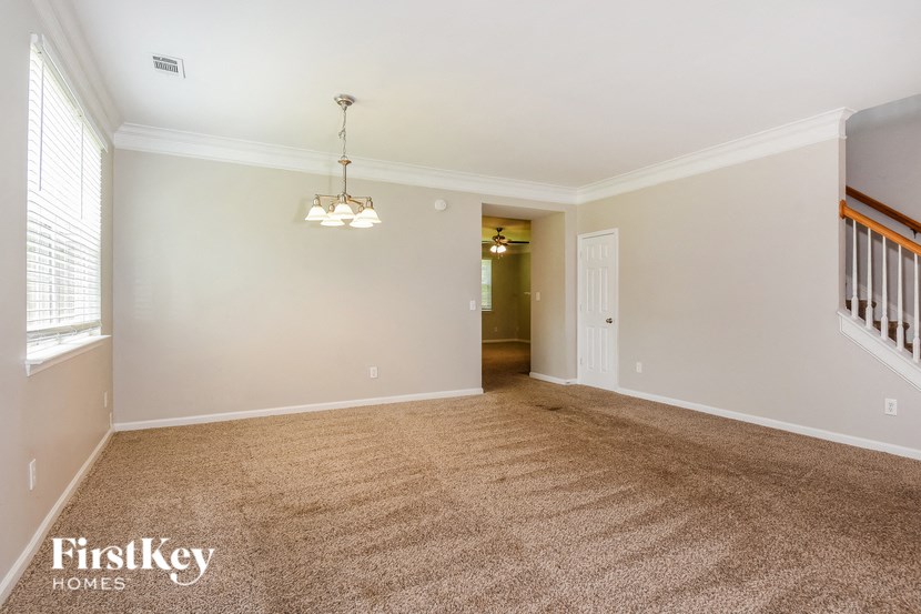 an empty living room with carpet and a staircase