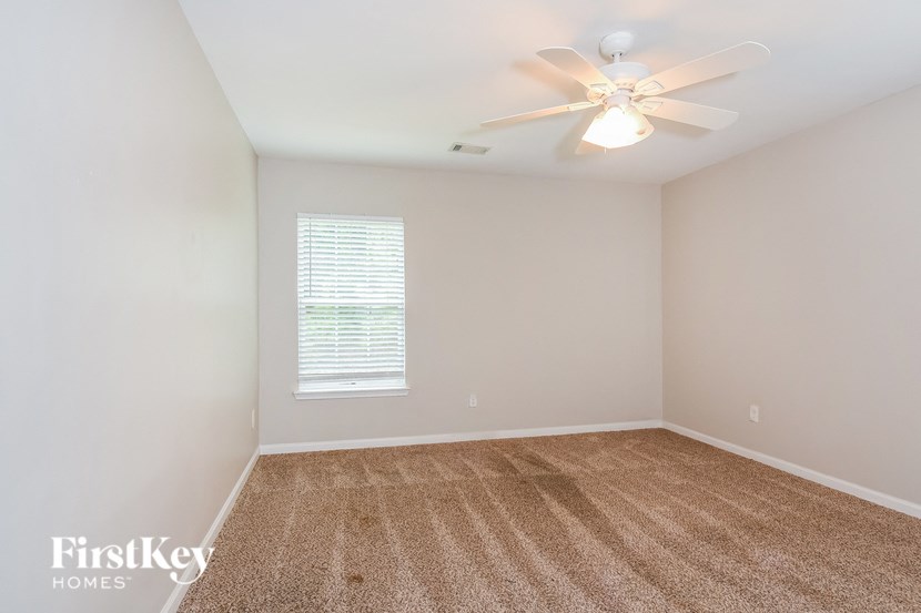 an empty living room with a ceiling fan and a window