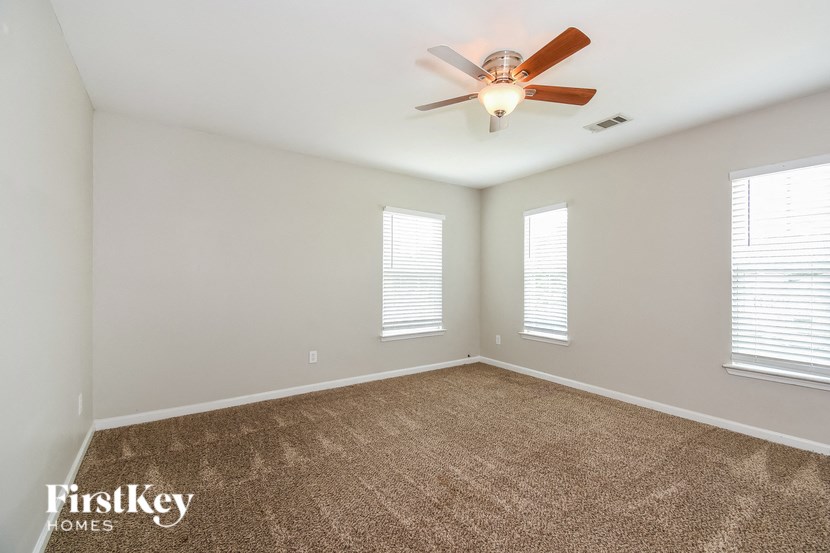 an empty living room with a ceiling fan and windows