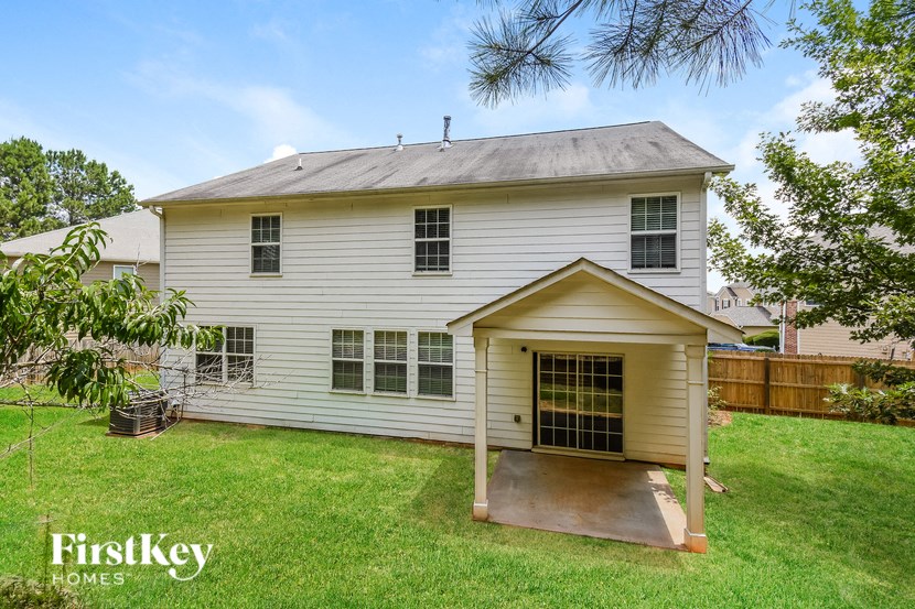 the front of a white house with a porch and a yard