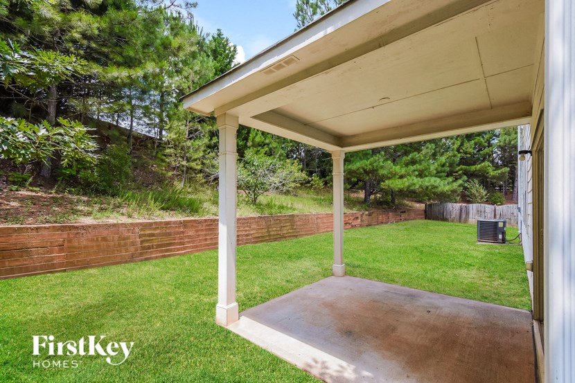 a covered porch with a lawn and a brick wall