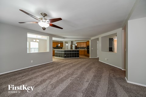 A spacious living room with a fan and carpeted floor.