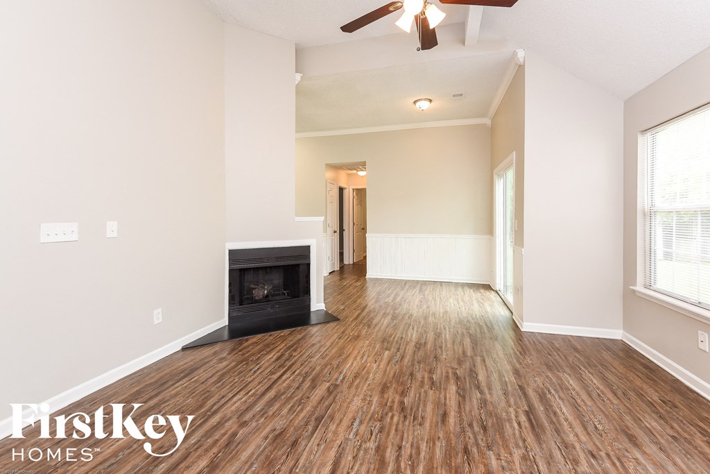 A spacious room with a fireplace and wooden flooring.
