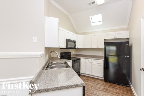 A kitchen with a black refrigerator and white cabinets.