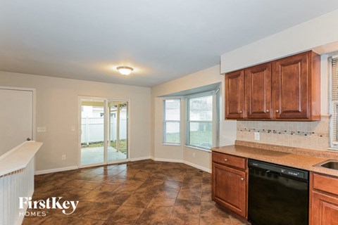 A kitchen with brown cabinets and a black dishwasher.