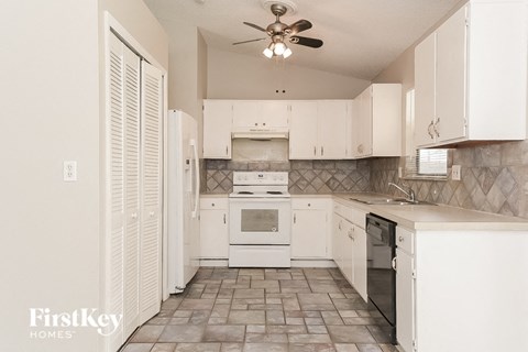 A kitchen with white cabinets and a tile floor.