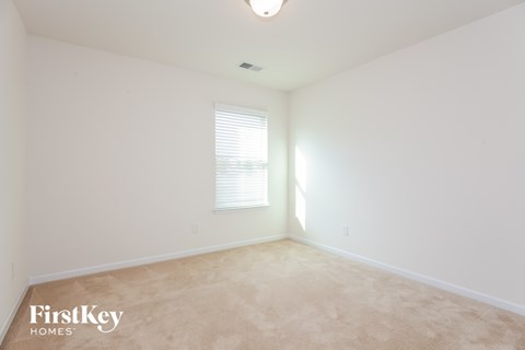 a bedroom with white walls and carpet and a window