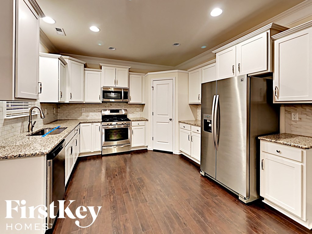 A kitchen with white cabinets and a refrigerator.