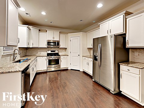 A kitchen with white cabinets and a refrigerator.
