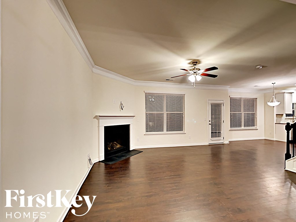 A spacious room with a fireplace and wooden floors.