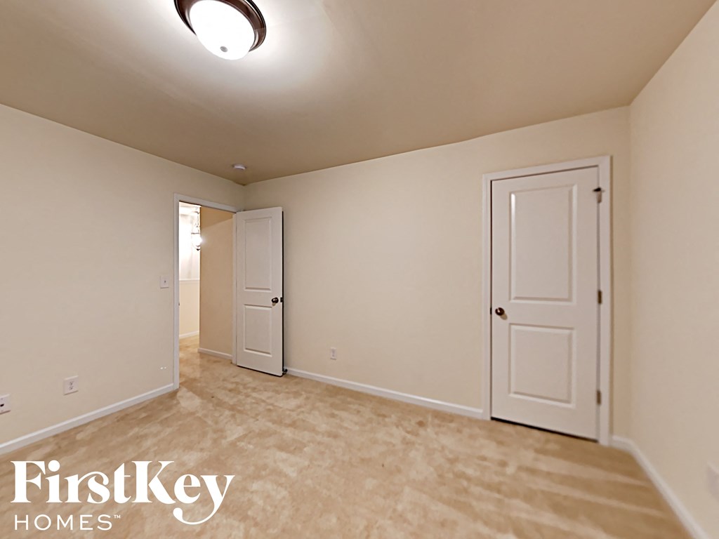 A bedroom with a carpeted floor and two doors.