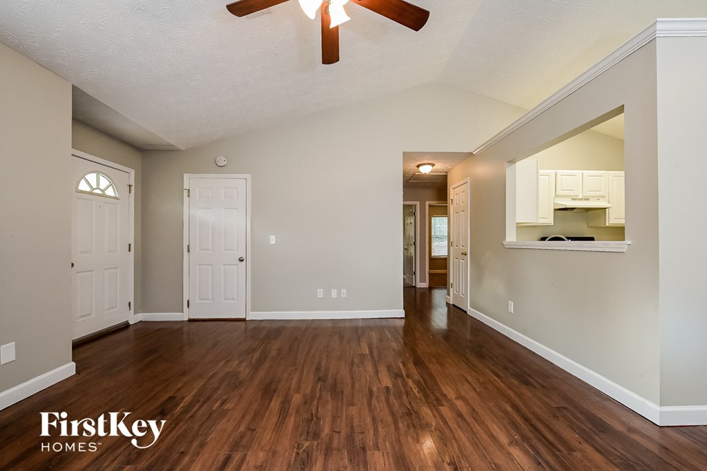 A spacious room with wooden floors and a ceiling fan.