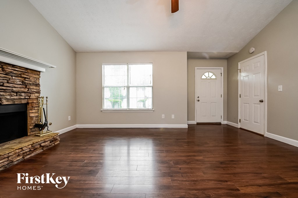 A room with a stone fireplace and wooden floors.