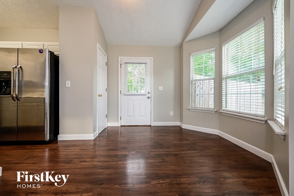 A kitchen with a black fridge and wooden floors.
