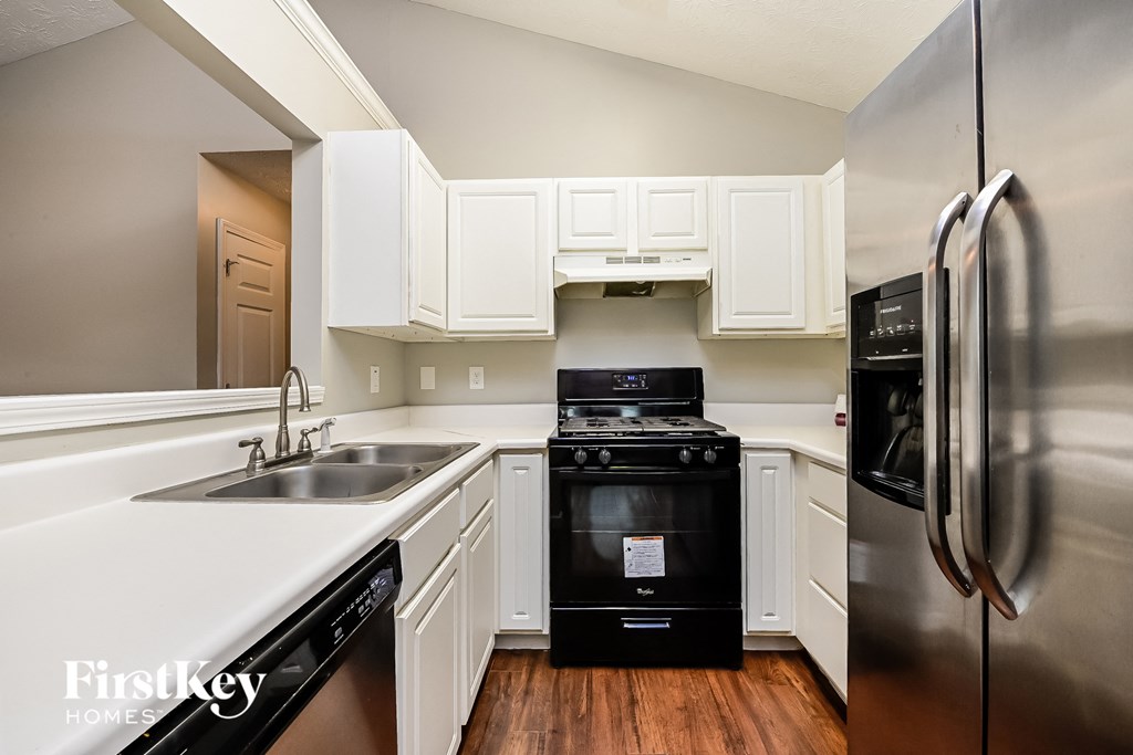 A kitchen with a black stove top oven and a stainless steel refrigerator.