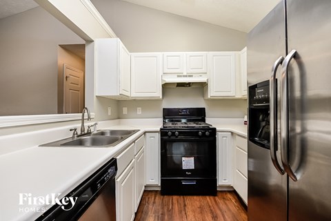 A kitchen with a black stove top oven and a stainless steel refrigerator.