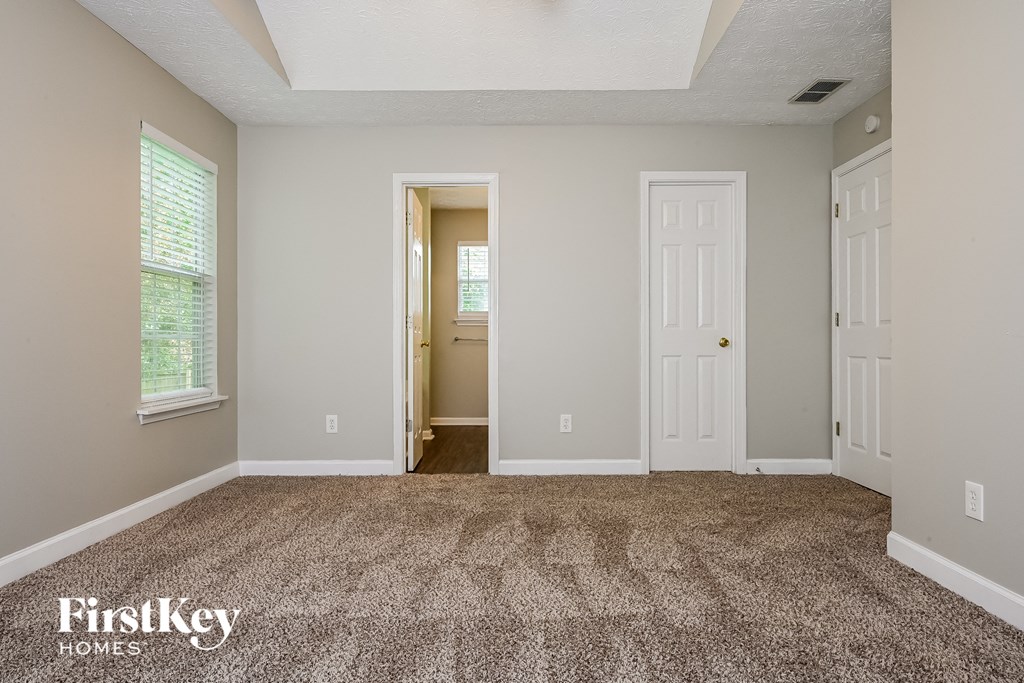 A room with a carpeted floor and two doors.