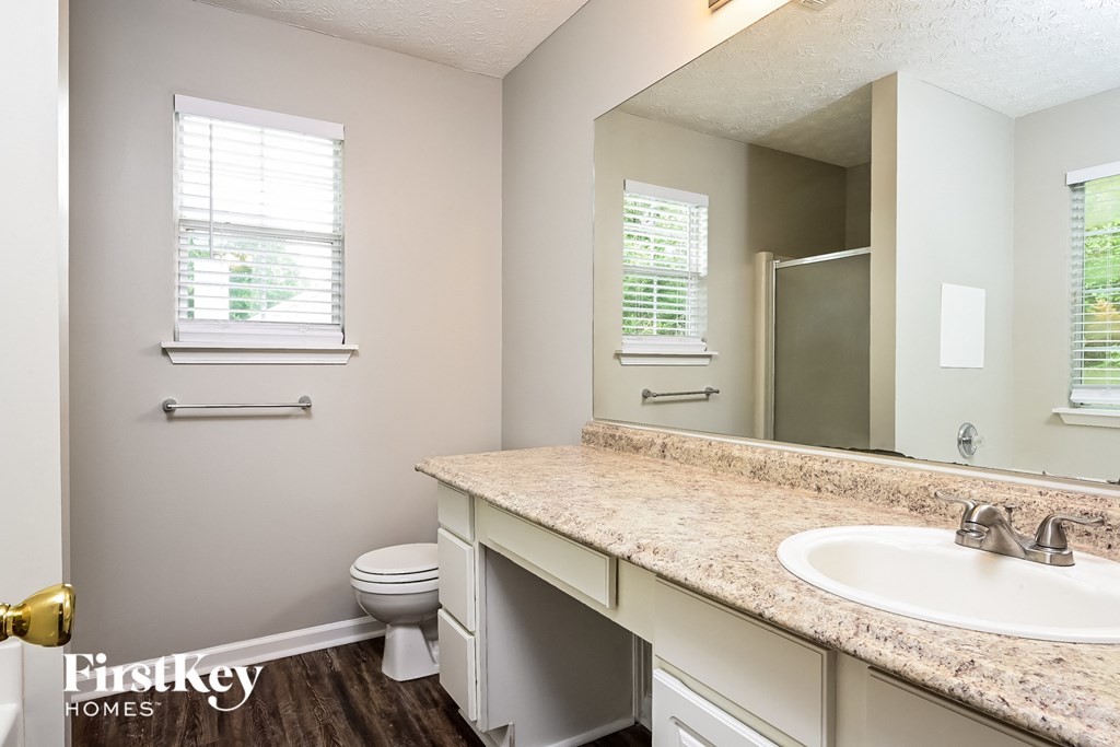 A bathroom with a toilet, sink, and mirror.