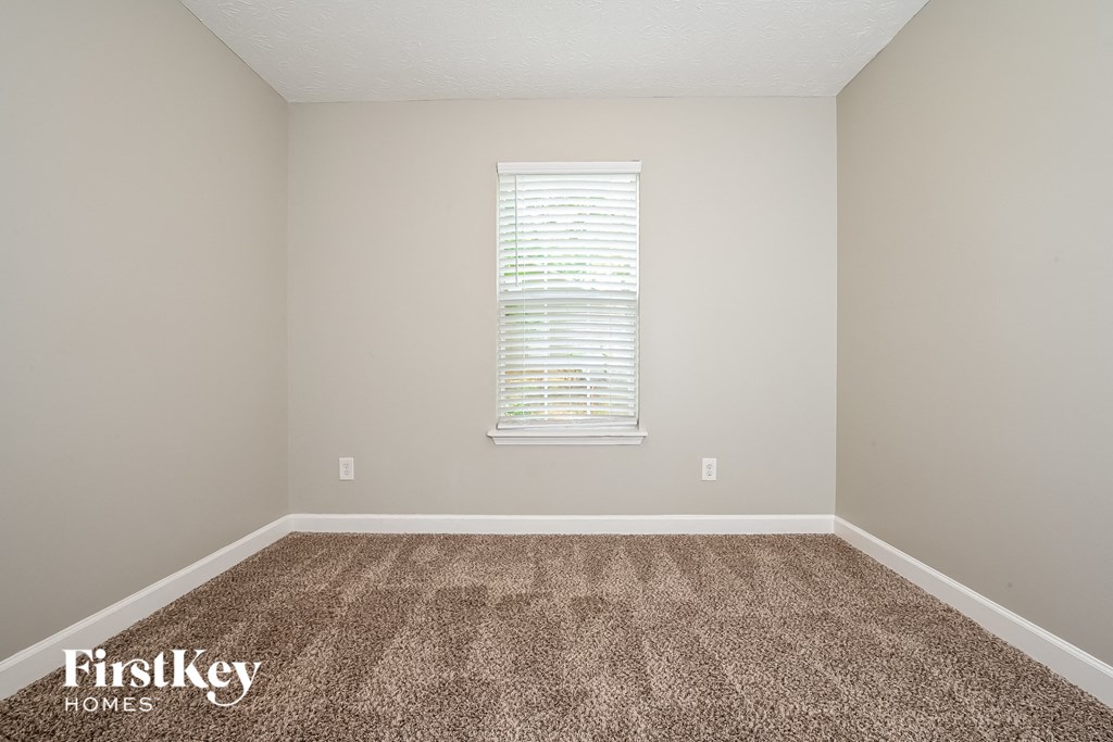 A room with a carpeted floor and a window with blinds.