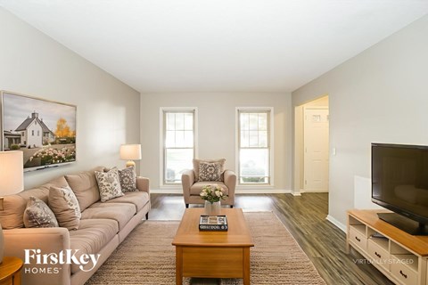 A living room with a couch, a chair, a coffee table, and a painting on the wall.