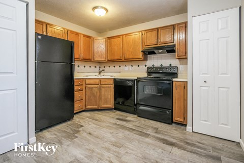 A kitchen with wooden cabinets and a black refrigerator.