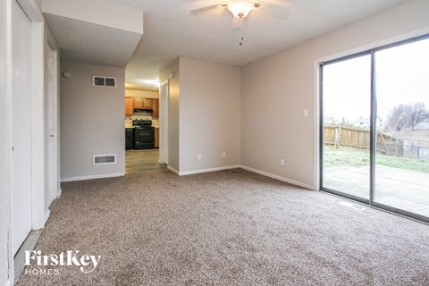 A spacious living room with a carpeted floor and a ceiling fan.