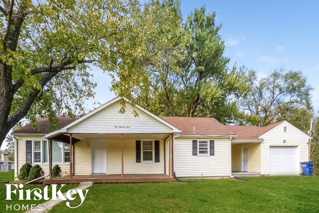 a small white house with a yard and trees