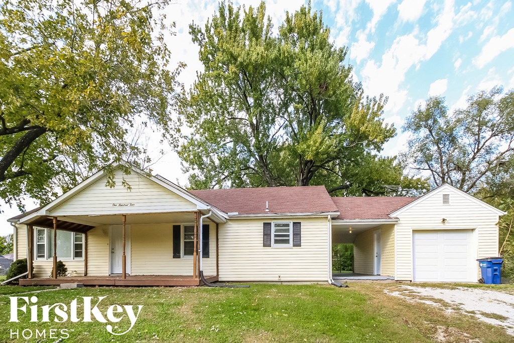 a small white house with a yard and some trees
