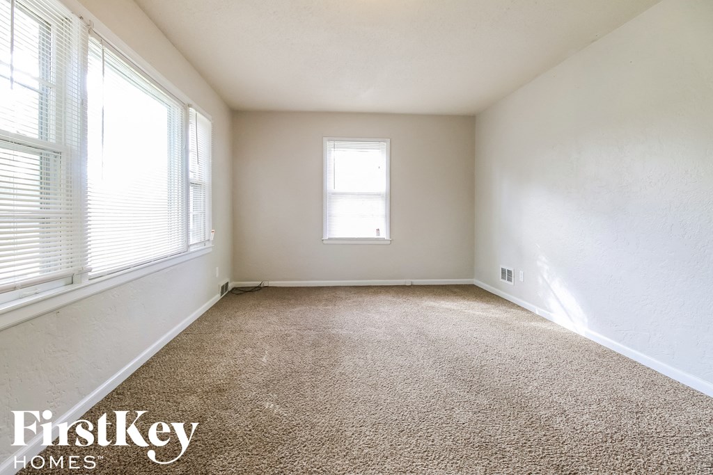 an empty room with carpet and two windows