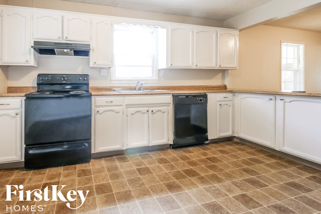 a kitchen with white cabinets and black appliances