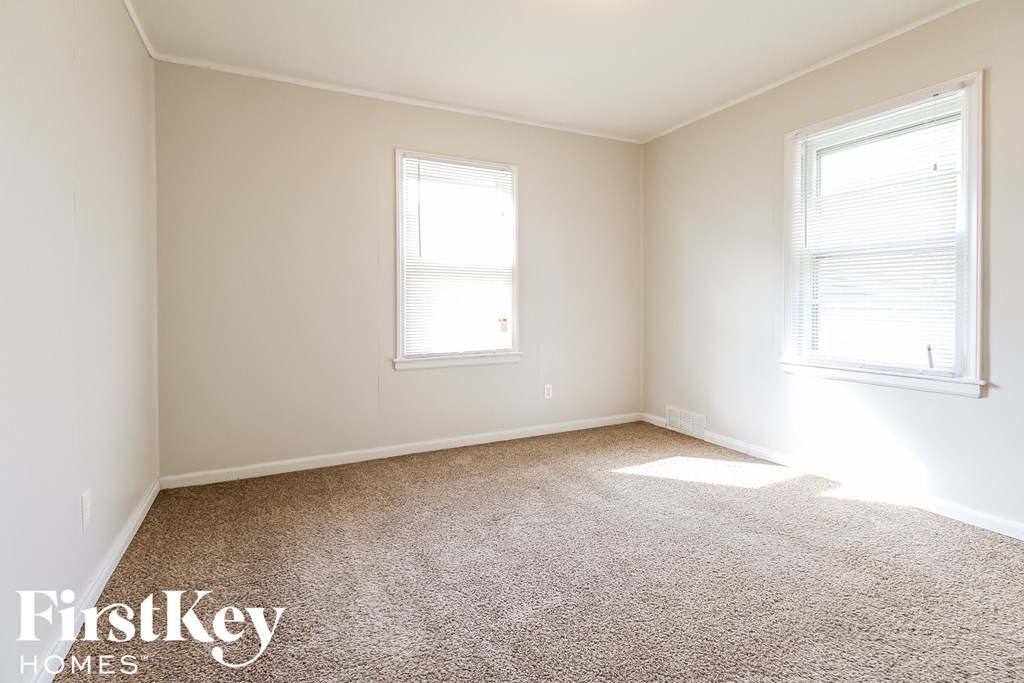 a bedroom with two windows and a carpeted floor