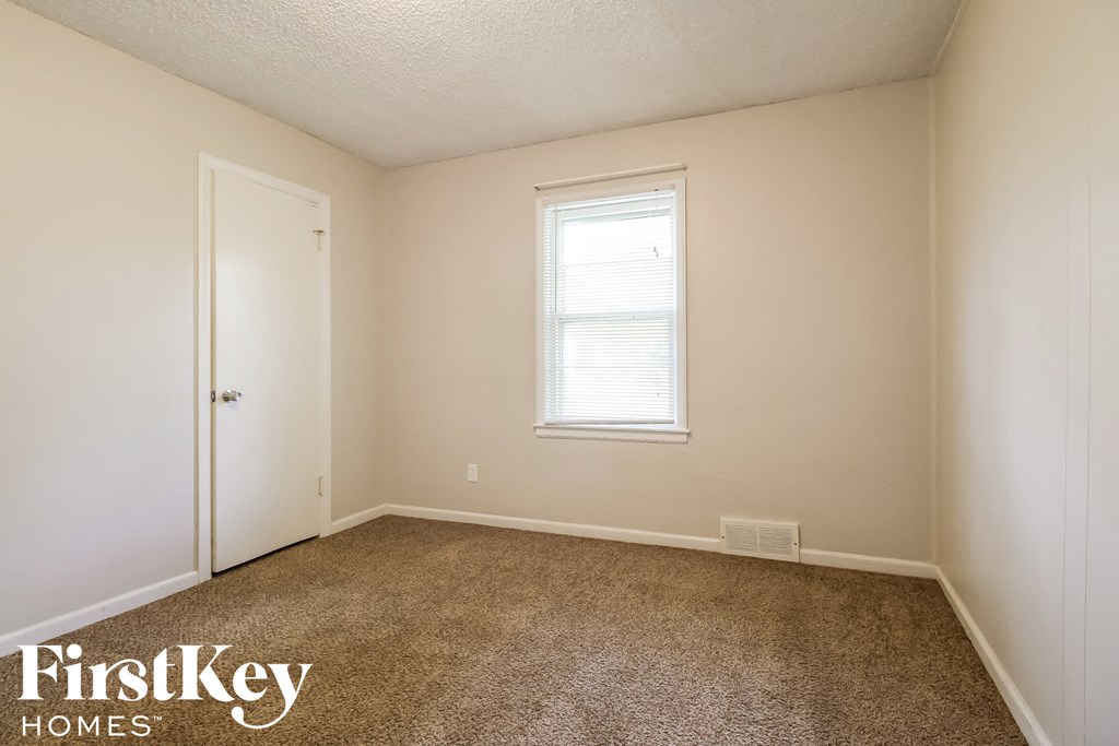 a bedroom with a carpeted floor and a window and a door