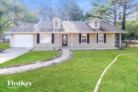 a small white house with a yard and a driveway