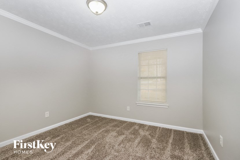 the spacious living room with carpeting and a window