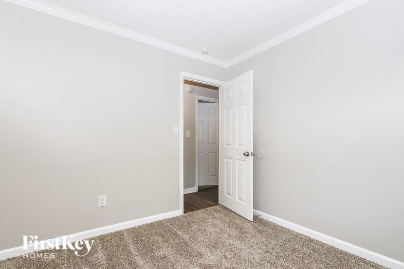 a bedroom with a white door and a carpeted floor
