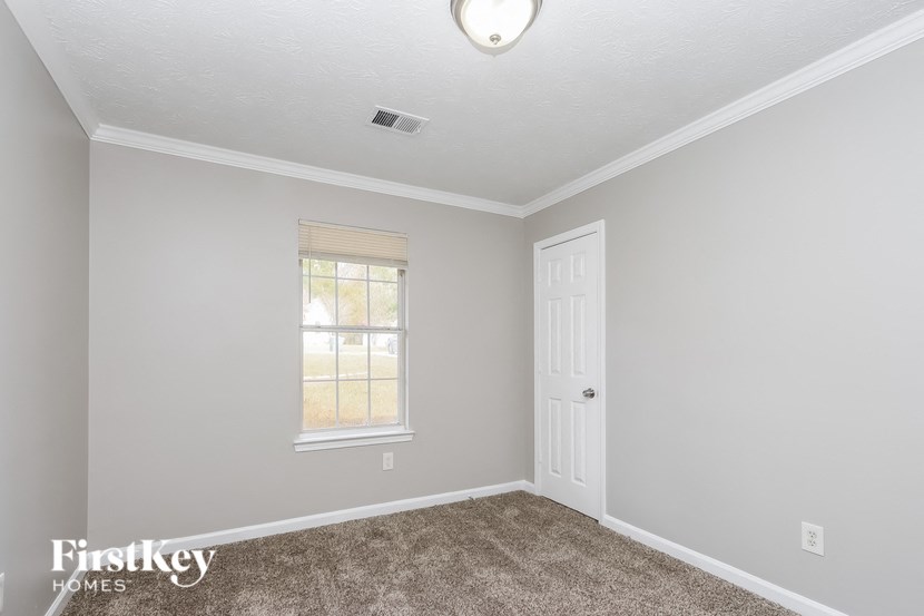 a bedroom with carpet and a white door and window