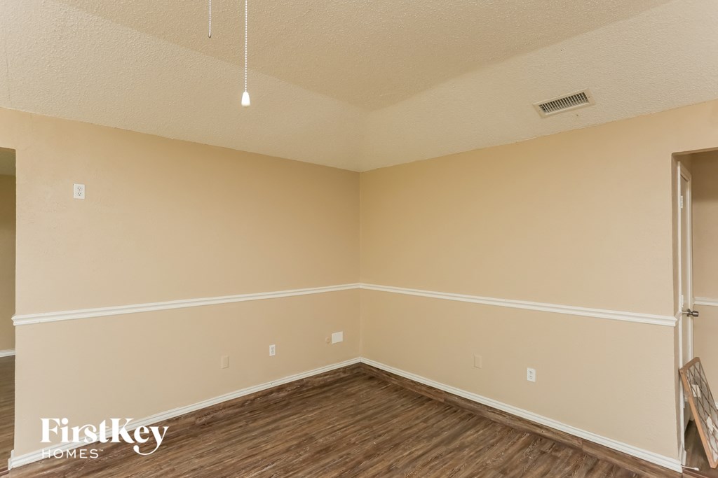 an empty room with wood flooring and beige walls